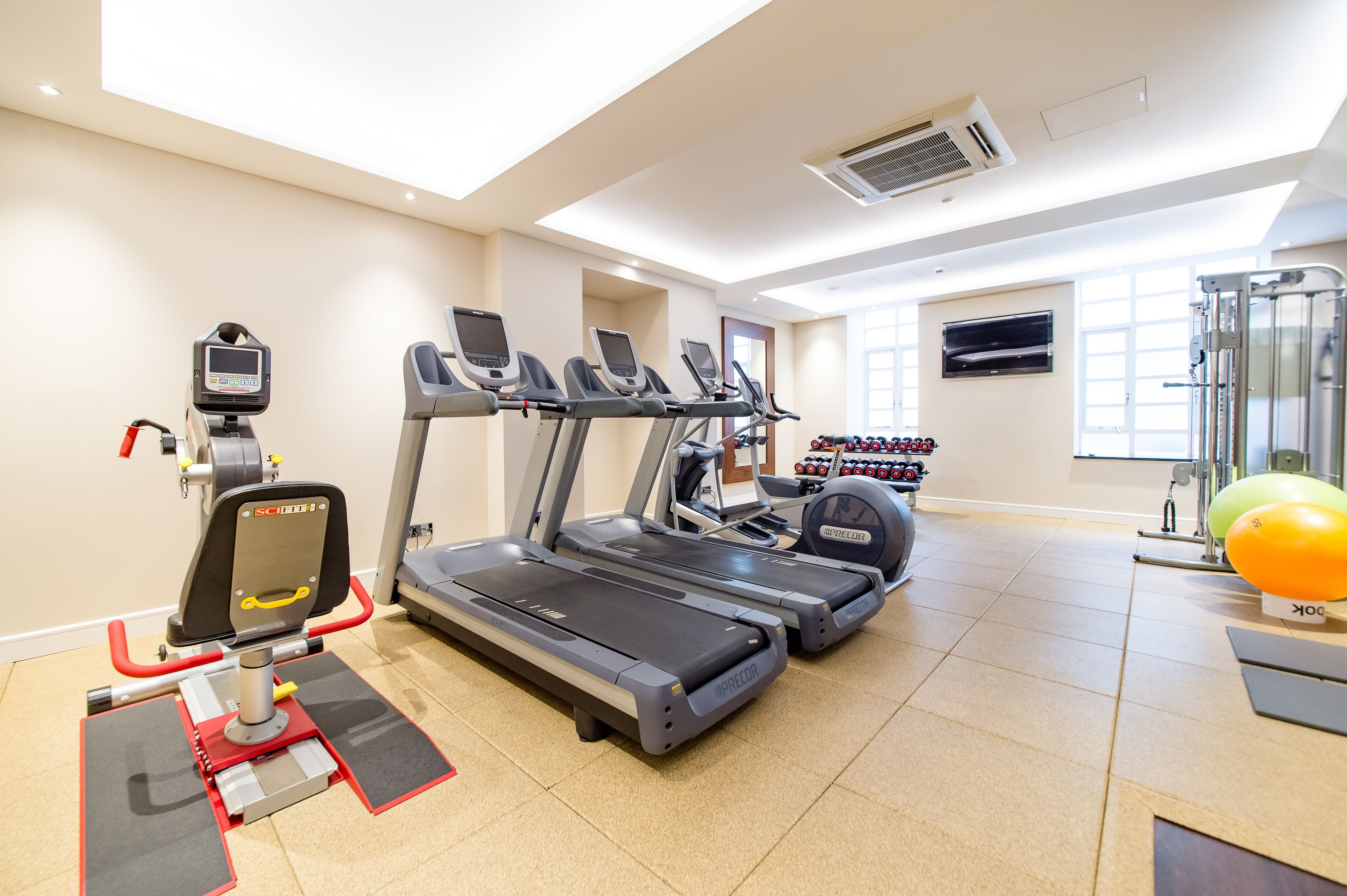 Un gimnasio con cintas de correr, una bicicleta estática y un banco de pesas.