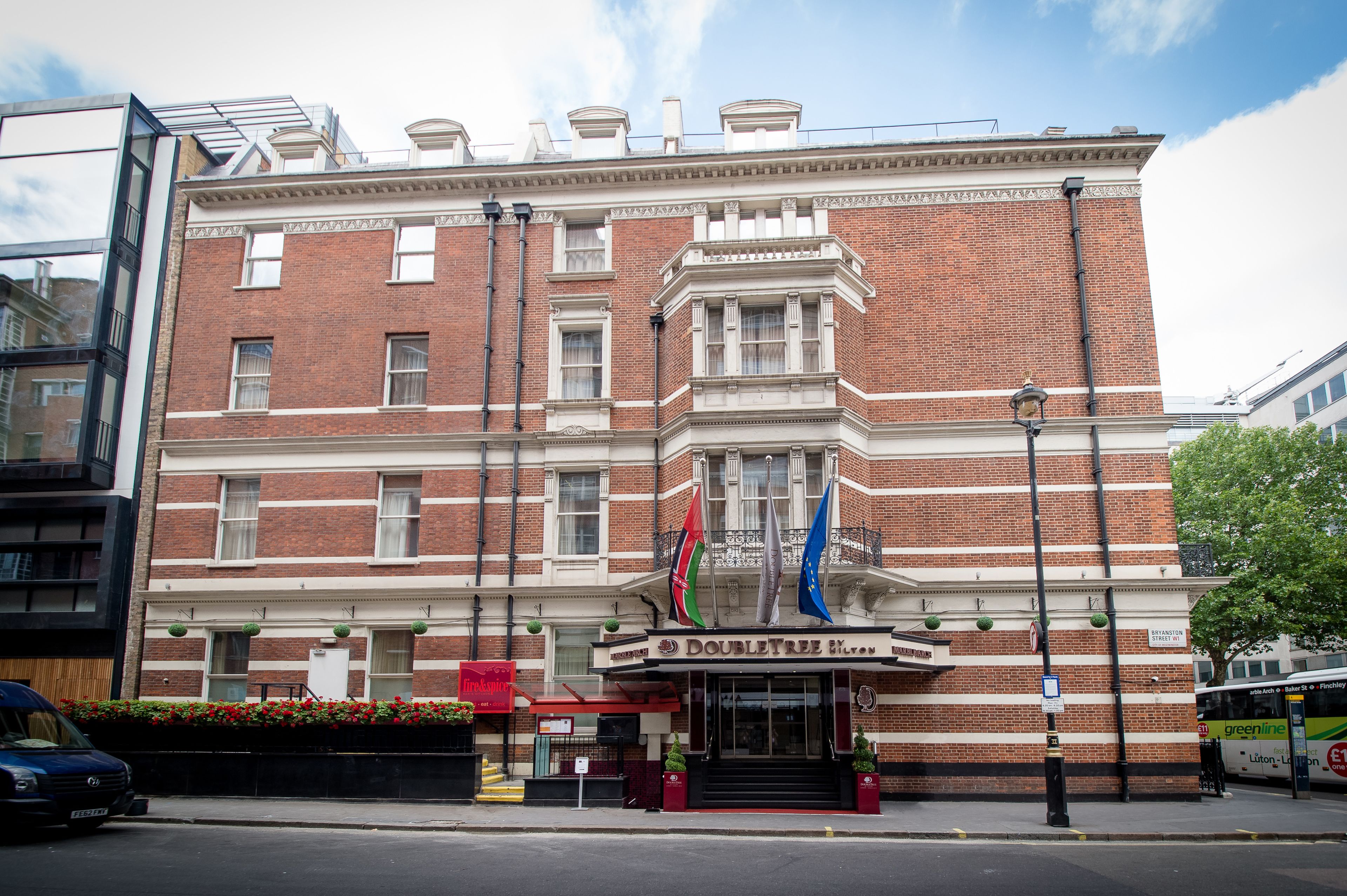 A historic building with a classic facade, a prominent entrance, and flags.