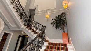 A grand staircase with ornate black railings and a colorful striped carpet. - Doubletree by Hilton London Marble Arch (London)