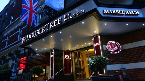 The exterior of the Doubletree by Hilton hotel with a prominent 'MARBLE ARCH' sign and a British flag. - Doubletree by Hilton London Marble Arch (London)