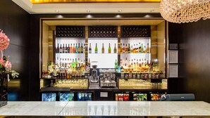 A bar area with shelves of various bottles, a coffee machine, and a seating area with a table and chairs. - Doubletree by Hilton London Marble Arch (London)