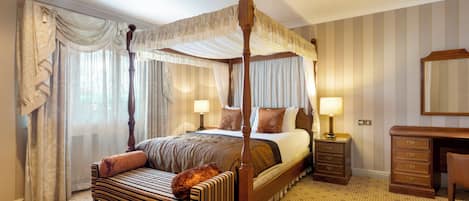 Un lit à baldaquin à quatre poteaux avec une structure en bois, un banc avec un coussin, une table de chevet avec une lampe et une commode avec des tiroirs.
