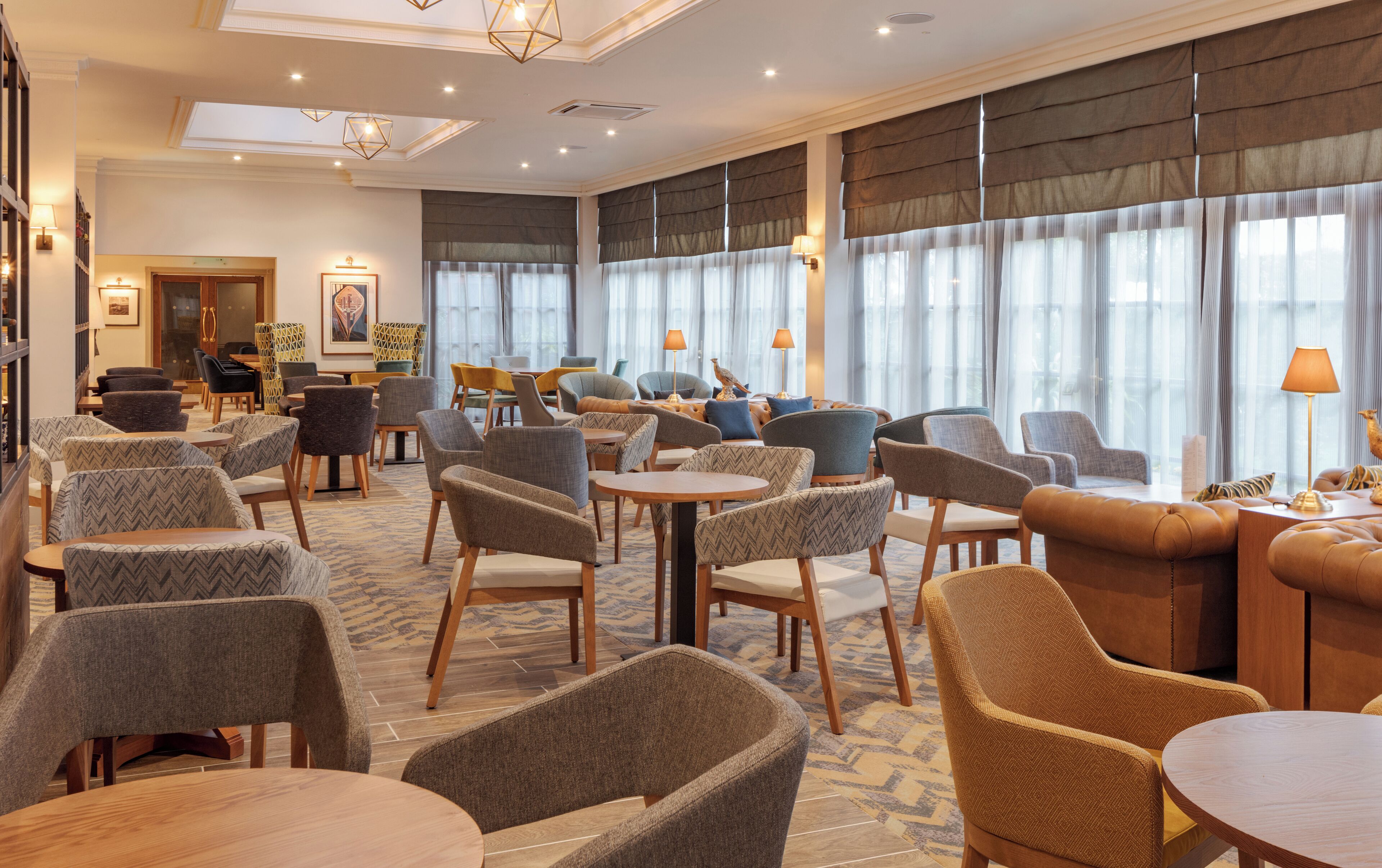 Een hotel lobby met verschillende zithoeken, inclusief banken en stoelen, gerangschikt rond een centrale salontafel.