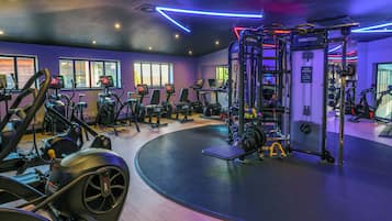 A gym with various exercise equipment, including treadmills and weight machines, and a wall-mounted squat rack.