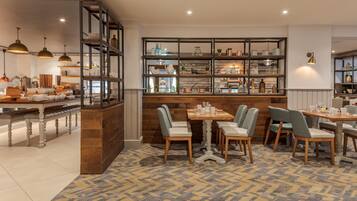 Een restaurant met een bar, houten meubels en een kamerbreed tapijt met dessin.