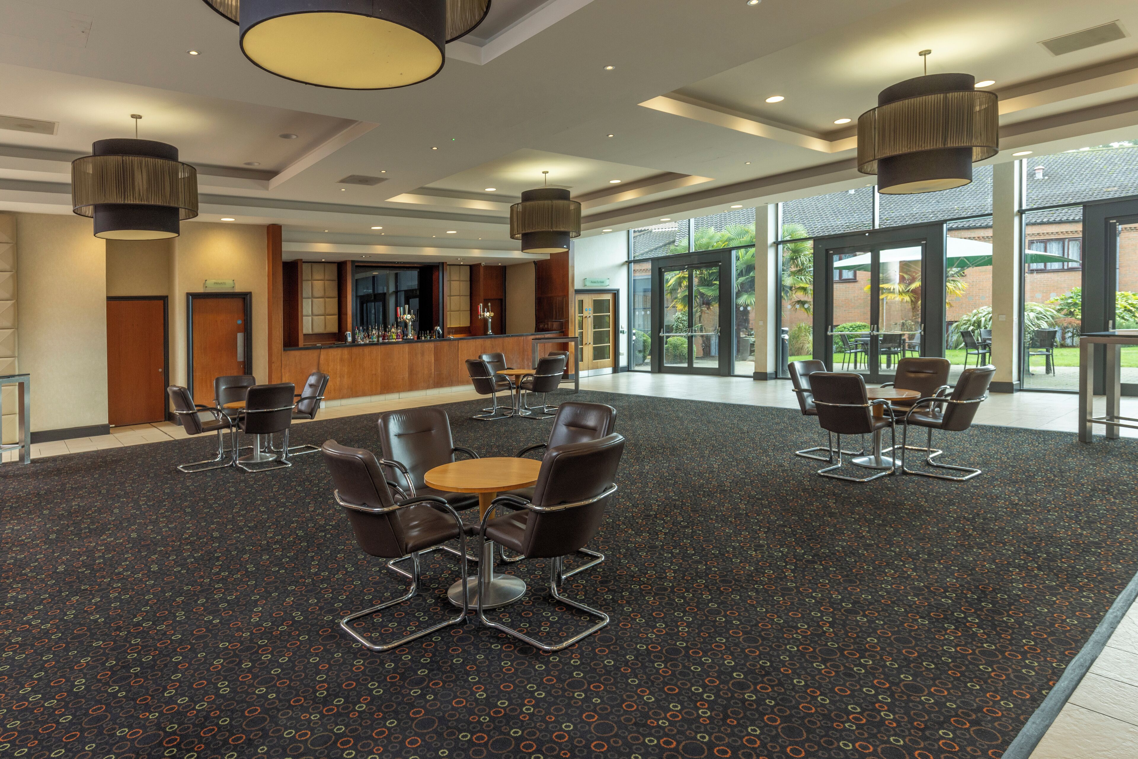 A spacious lobby with a reception desk, seating area, and large windows offering a view of the outdoors.