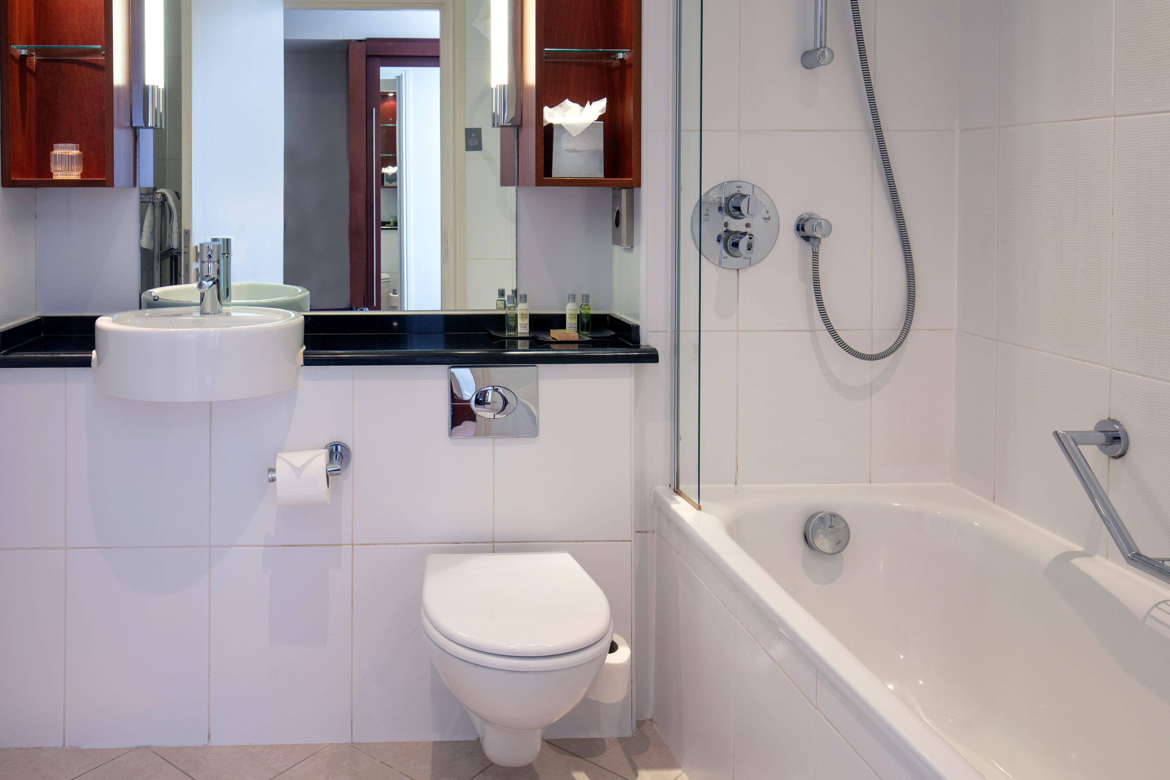 Et moderne badeværelse med toilet, vask og badekar, alt i hvidt.