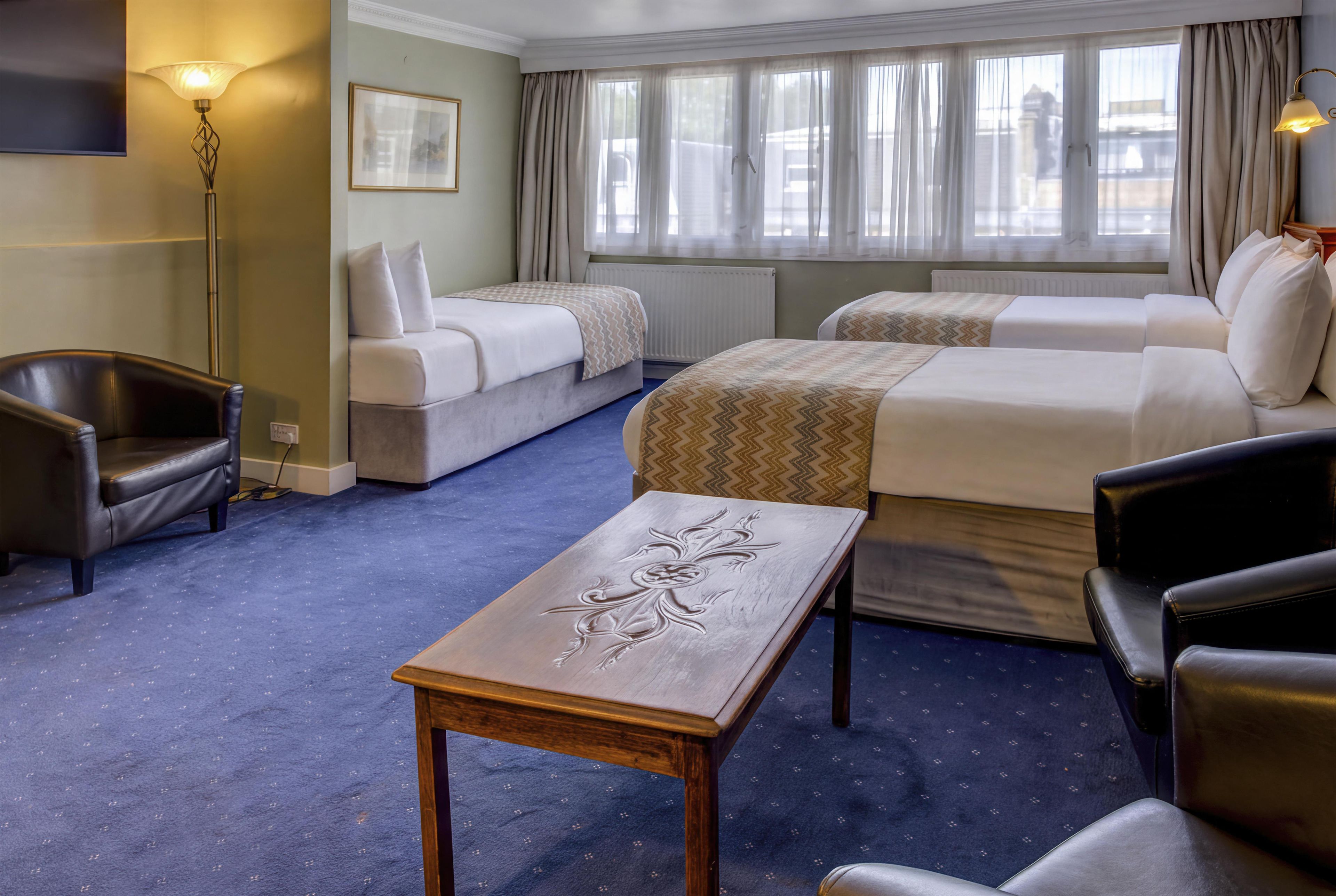 A hotel room with a bed, a sofa, a desk, and a chair.