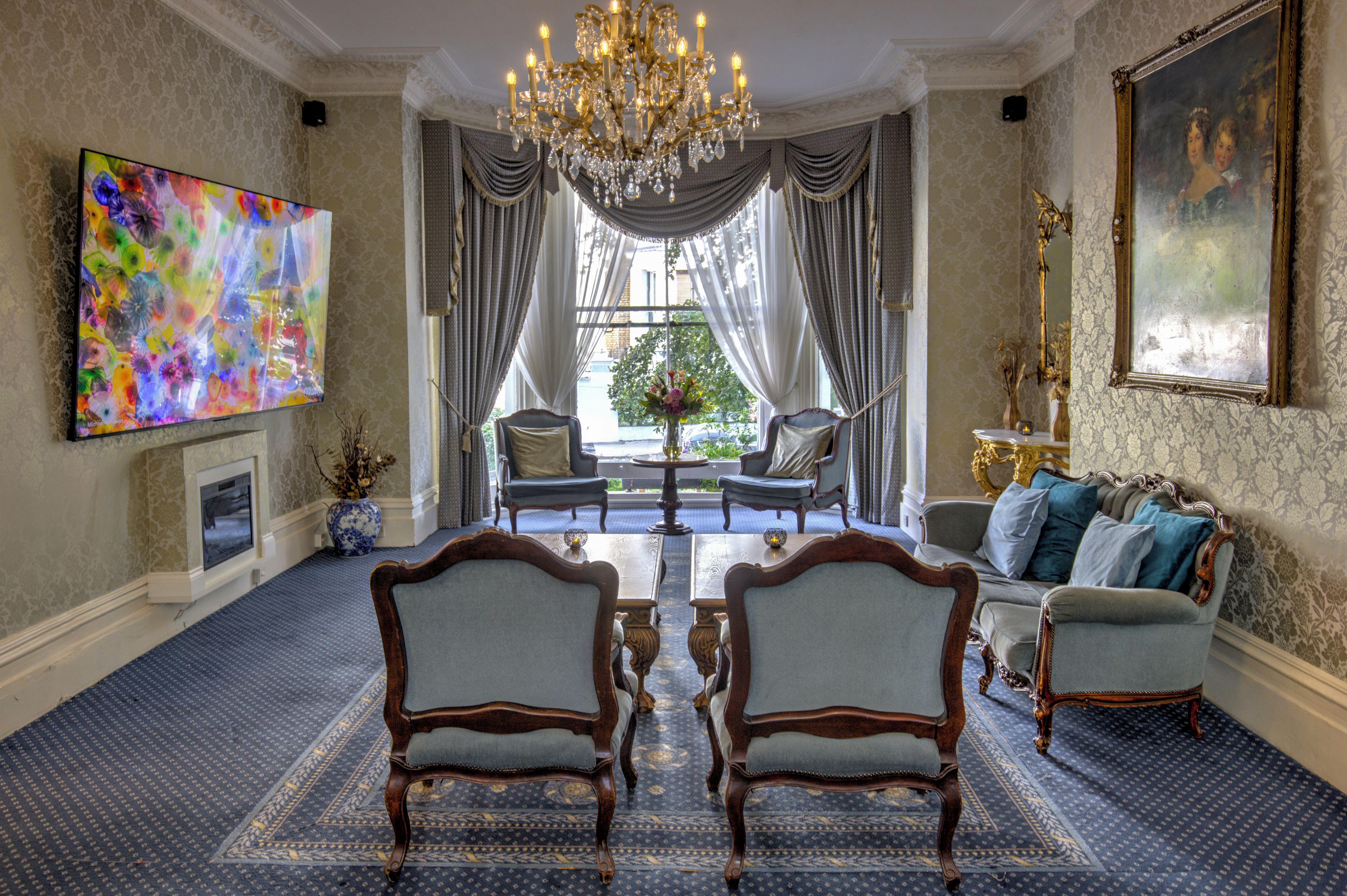 A formal dining room with a chandelier, two chairs, a table, and a sofa.