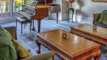 A grand room with a grand piano, a chandelier, and a large painting on the wall.