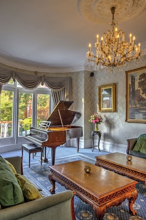 A grand room with a grand piano, a chandelier, and a large painting on the wall. - Best Western Swiss Cottage Hotel (London)