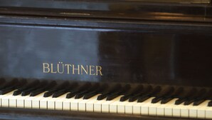 A grand piano with the brand name "BLUTHNER" on its lid.