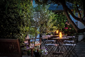 An outdoor seating area with tables and chairs, surrounded by greenery and plants. - Best Western Swiss Cottage Hotel (London)