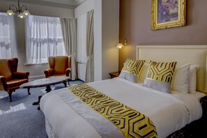 A hotel room with a large bed, two armchairs, a small table, and a painting on the wall. - Best Western Swiss Cottage Hotel (London)