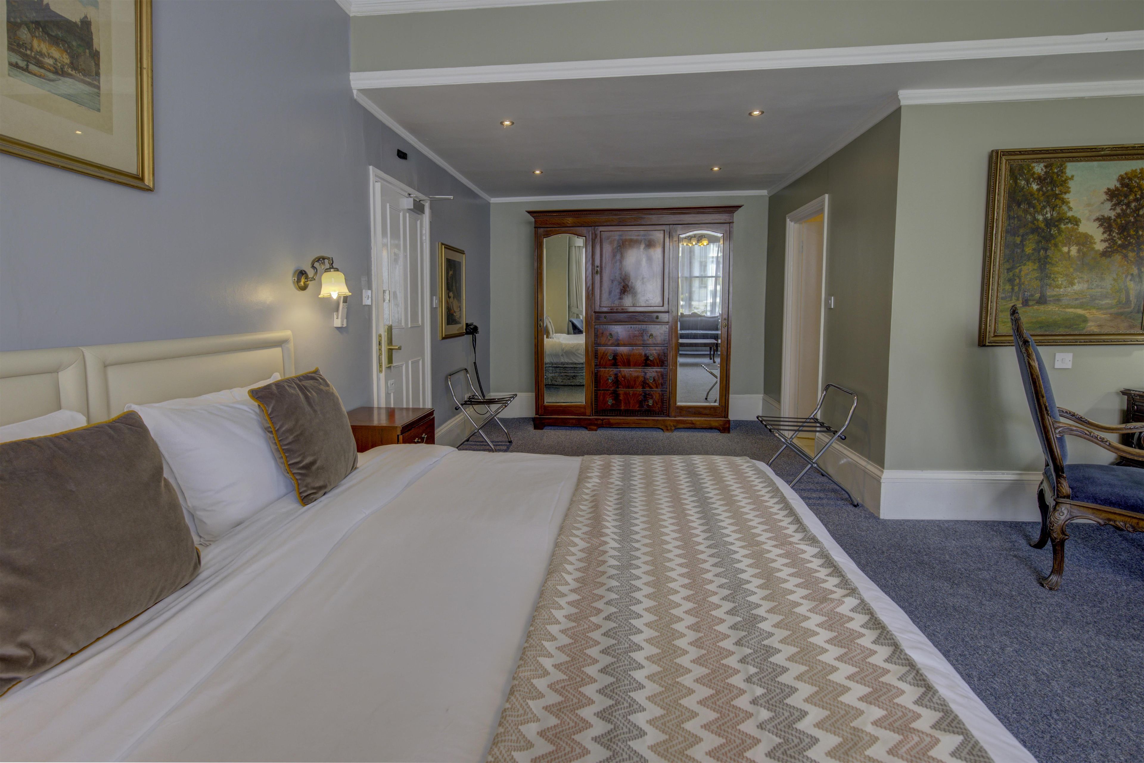 Habitación de hotel con una cama grande, un escritorio, una silla y un cuadro en la pared.