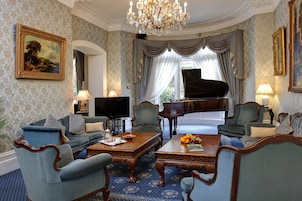 A grand room with a grand piano, elegant furniture, and a chandelier.