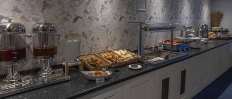 A buffet setup with various food items and beverage dispensers.