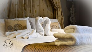 A neatly made bed with towels arranged in a heart shape, a lamp, and a decorative wall lamp. - Pennine Manor Hotel (Huddersfield)