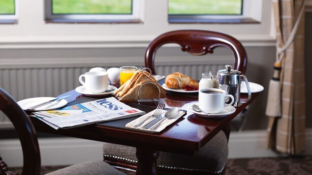 A breakfast table with croissants, coffee, and a newspaper. - Pennine Manor Hotel (Huddersfield)