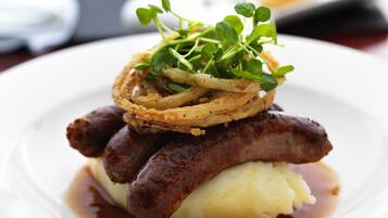 A plate of food with sausages, mashed potatoes, and onion rings.