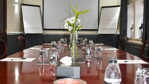 A conference room with a long table, chairs, a projector screen, and a floral arrangement. - Pennine Manor Hotel (Huddersfield)