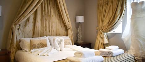 A neatly made bed with white linens, a striped bedspread, and a canopy bed with draped curtains.