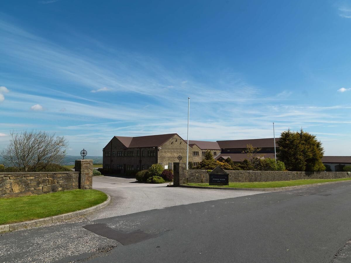 A building with a stone facade, a curved driveway, and a grassy area.