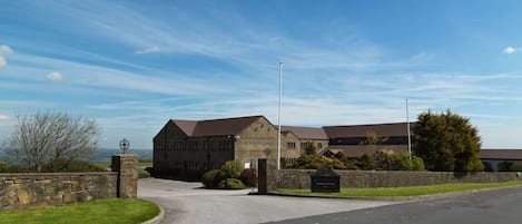 A building with a stone facade, a curved driveway, and a grassy area.