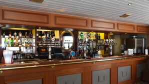 A bar area with wooden cabinets, a mirror, and various bottles and glasses. - Pennine Manor Hotel (Huddersfield)