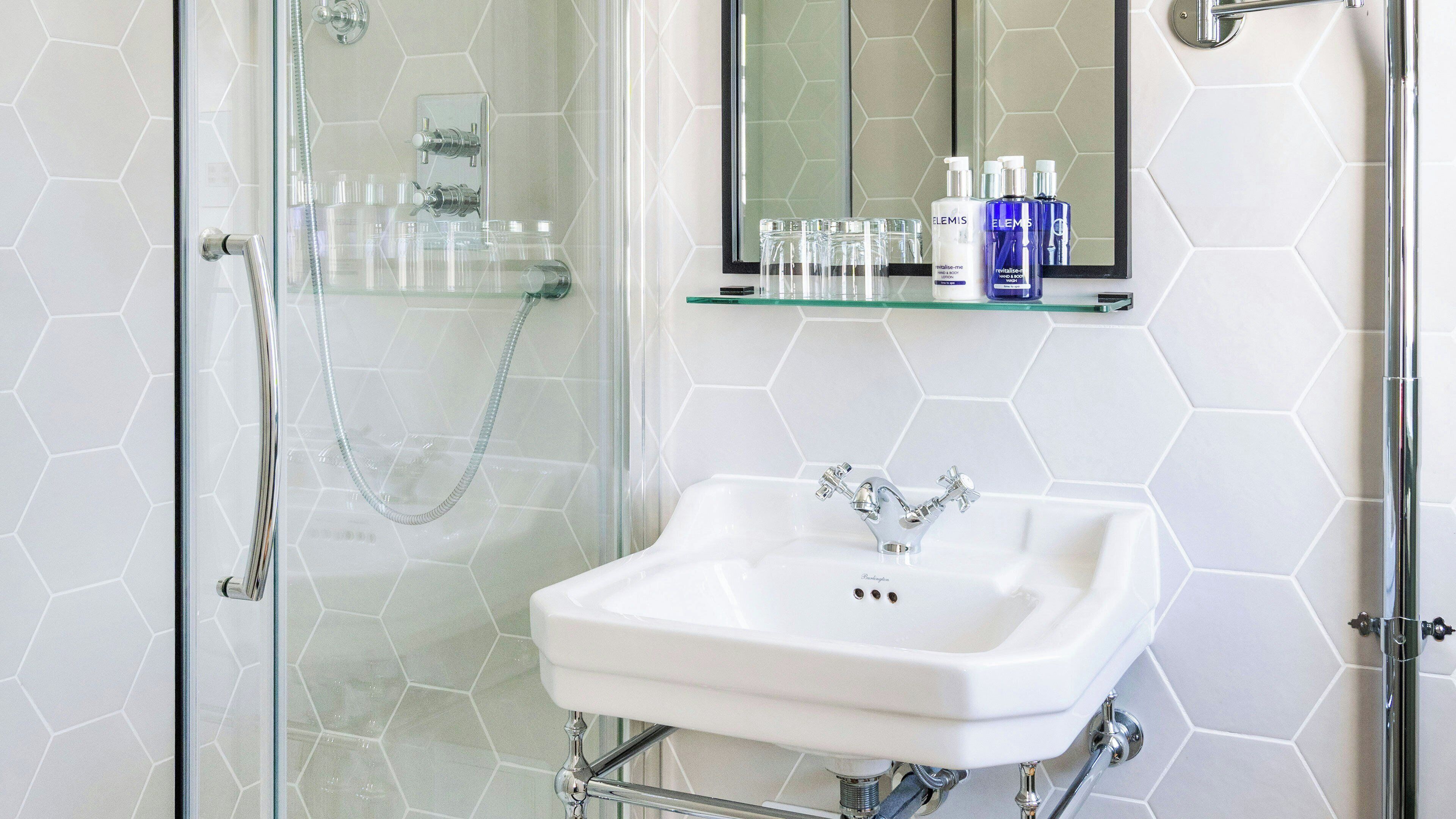 A bathroom with a glass shower enclosure, a white sink, and a mirror above it.