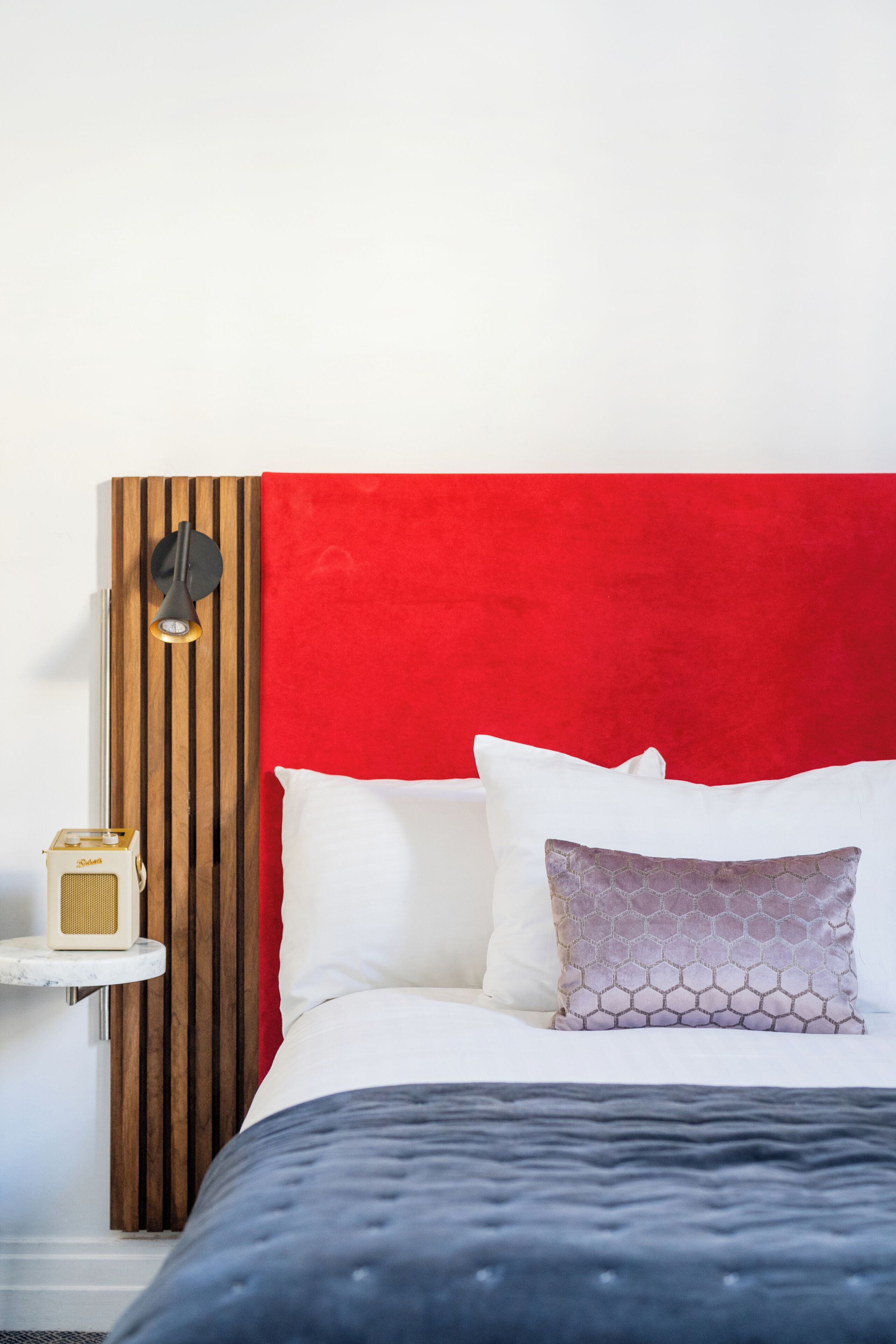 A bed with a red headboard, white pillows, and a patterned pillow.