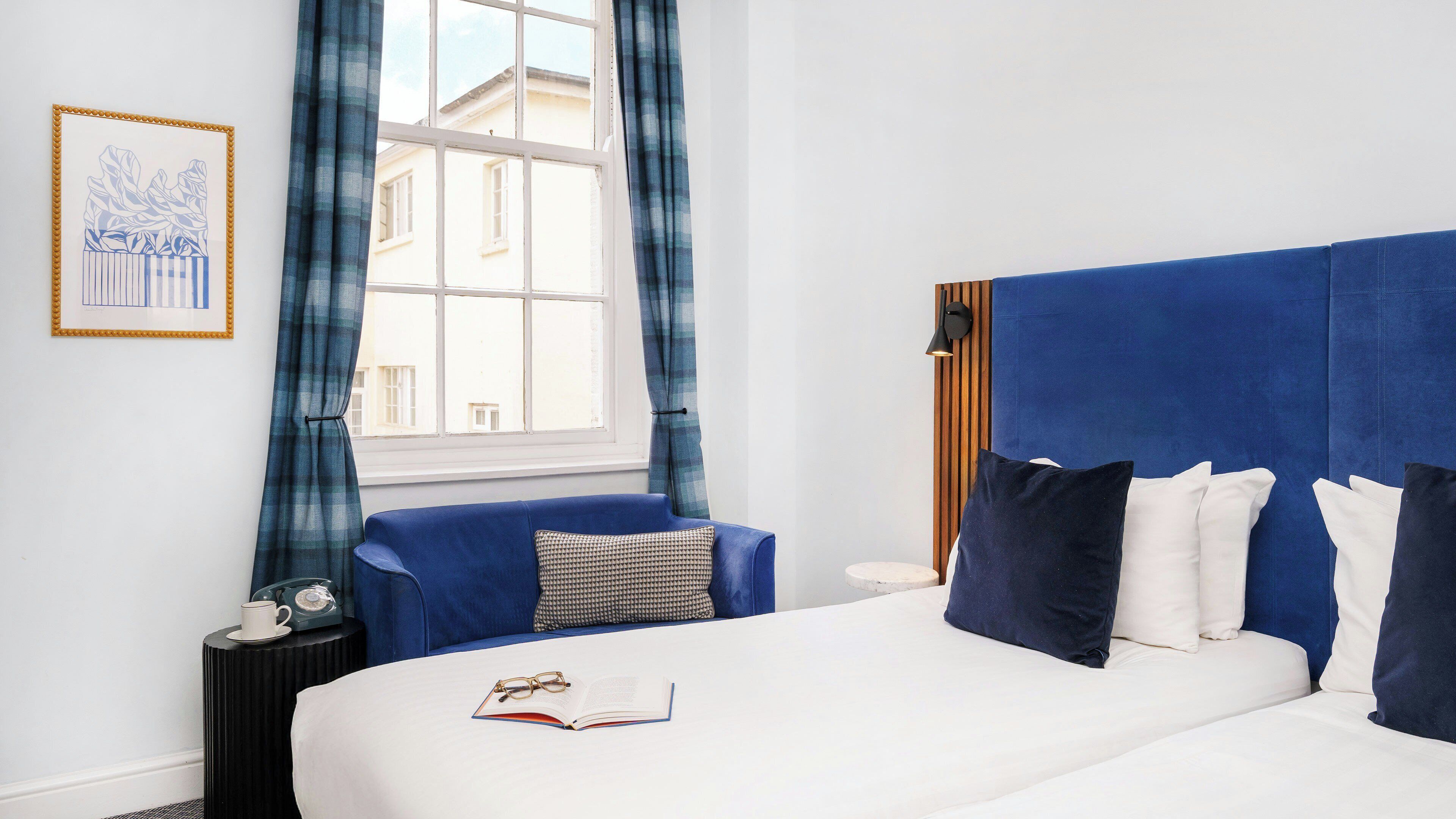 A bedroom with a large bed, a bedside table, a lamp, and a window with curtains.