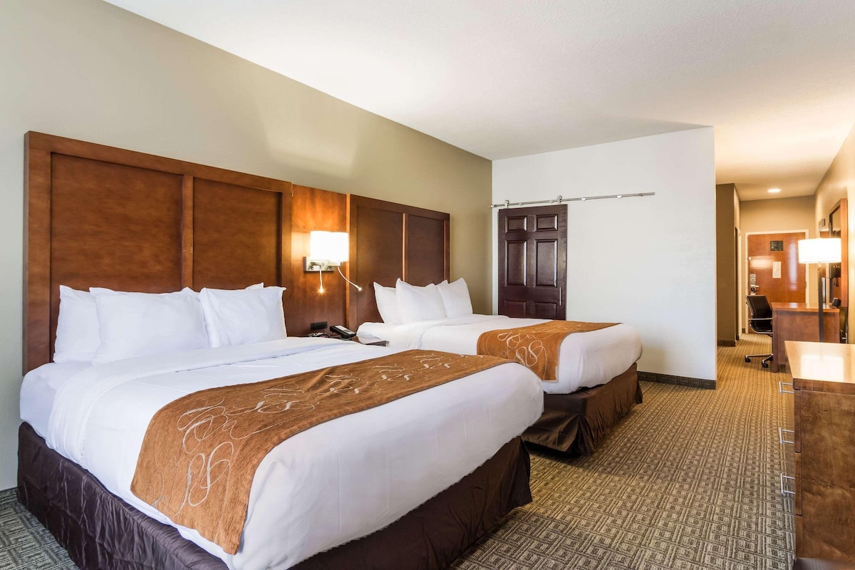 A hotel room with two beds, a desk, and a bathroom.