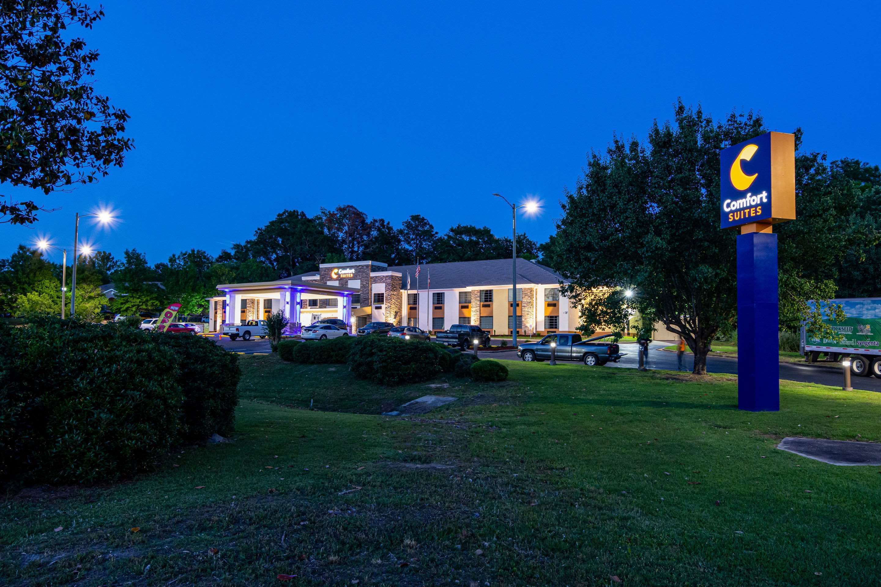 Een Comfort Suites hotel met een goed verlichte ingang, parkeerplaats en een groot bord.