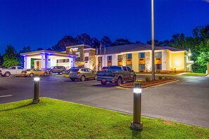 Ein Hotel mit Tankstelle, mehreren Parkplätzen und einem gut beleuchteten Eingang.