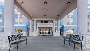 A covered entrance with two benches, large columns, and a building with blue and white exterior walls. - Comfort Inn Birmingham - Irondale (Birmingham)