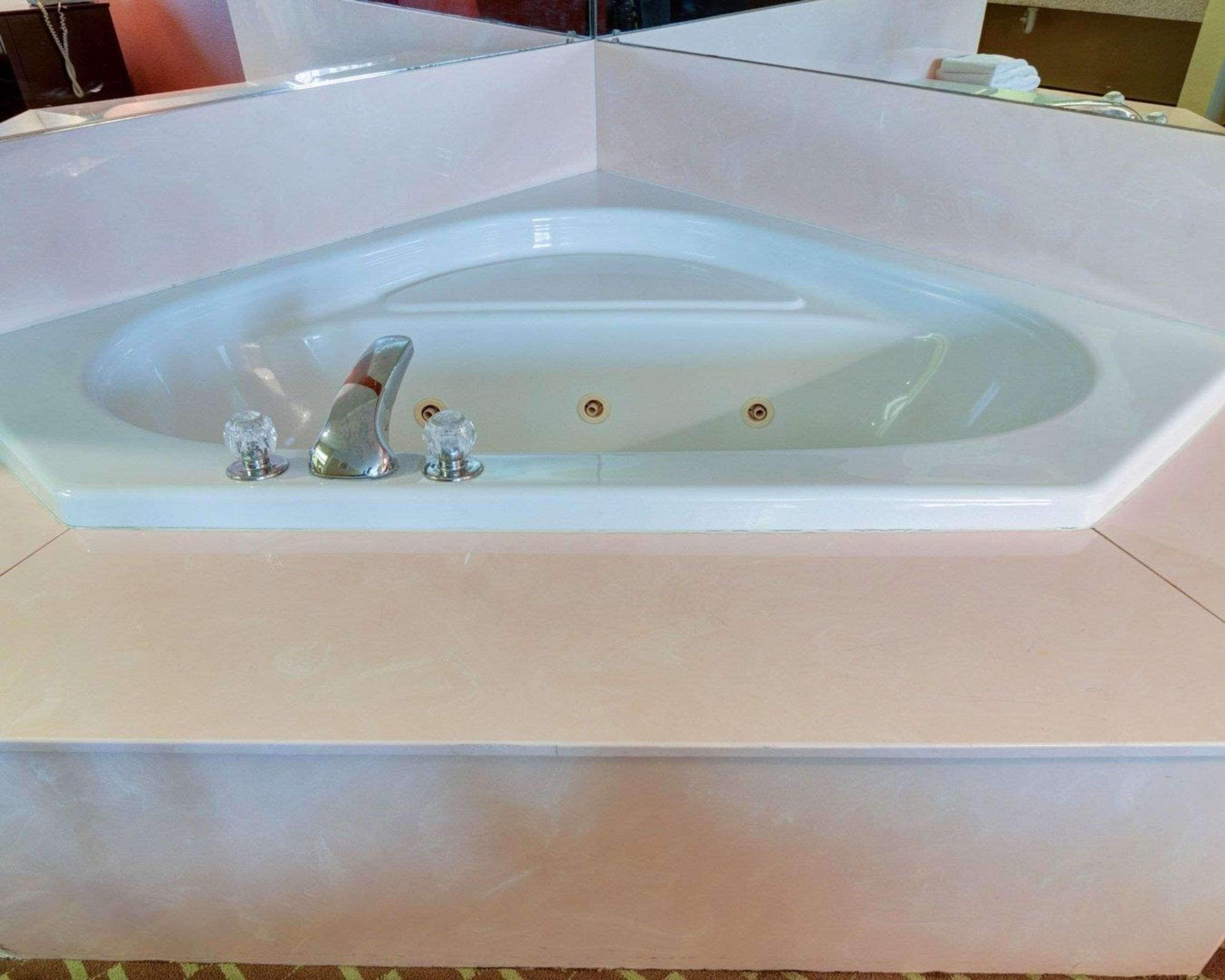 A large, rectangular, white bathtub with two faucets and a single drain.