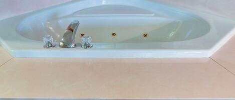 A large, rectangular, white bathtub with two faucets and a single drain.