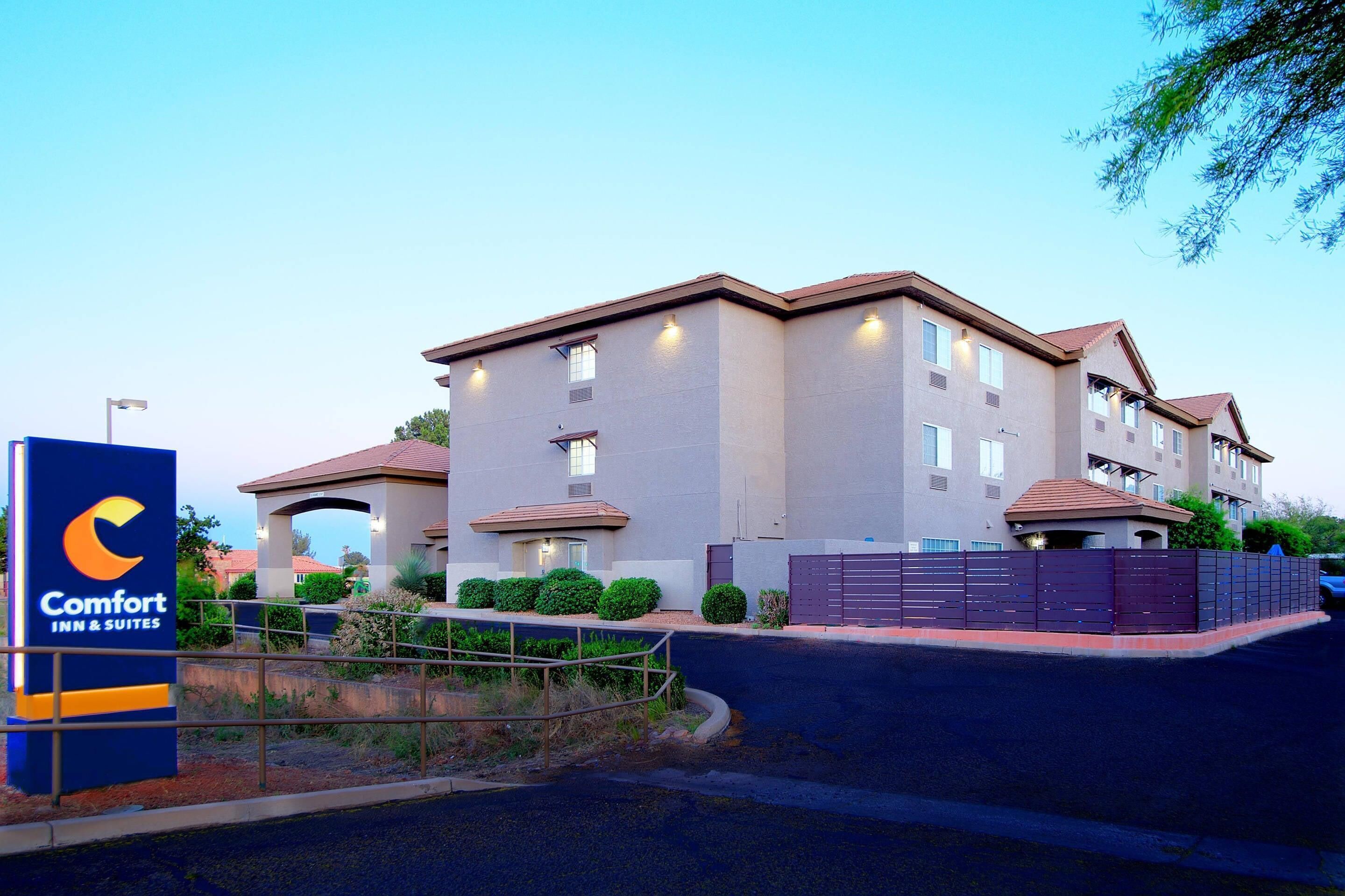 A multi-story hotel with a sign for Comfort Inn & Suites, featuring a modern architectural design with a flat roof and a gated entrance.