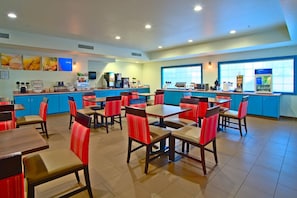 A restaurant with multiple tables and chairs, a counter with a beverage dispenser, and a large window. - Comfort Inn & Suites Sierra Vista Near Ft Huachuca (Sierra Vista)