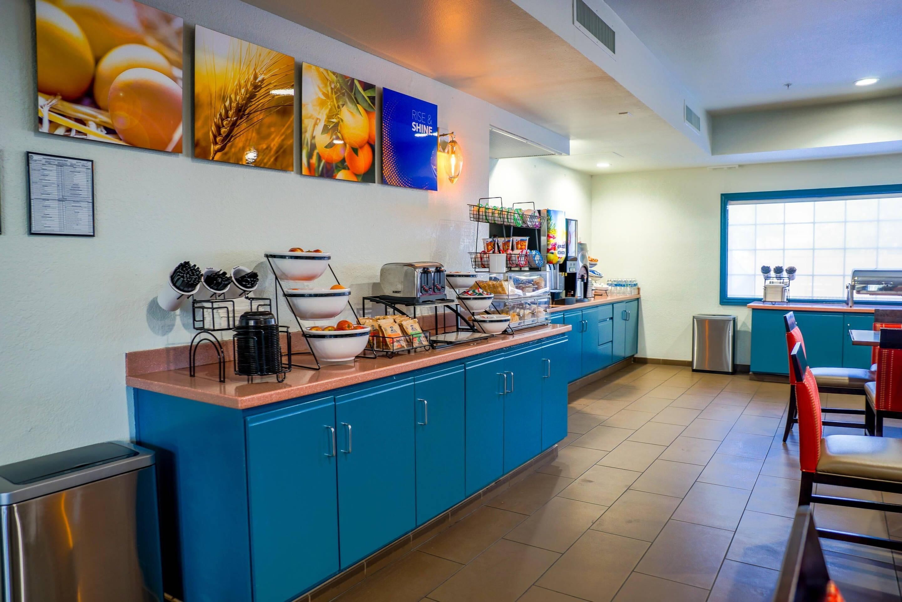 A breakfast bar with various food items, a coffee machine, and a seating area with chairs.