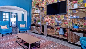 A modern living room with a blue wall, a flat-screen TV, and a variety of decorative items on shelves. - Comfort Inn & Suites Sierra Vista Near Ft Huachuca (Sierra Vista)