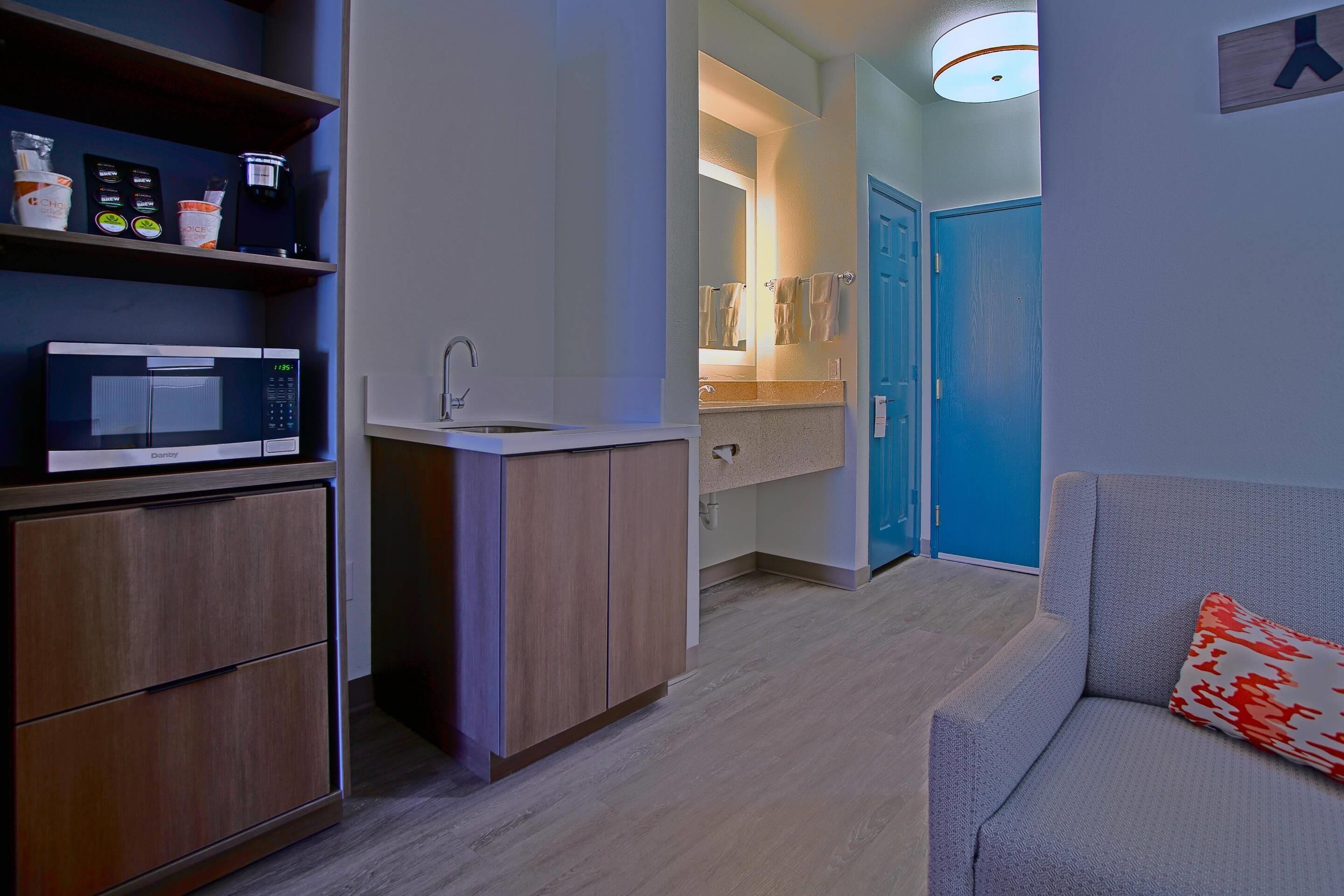 A compact kitchenette with a microwave, sink, and storage cabinets.
