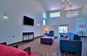 A spacious living area with a flat-screen TV, a blue sofa, a red chair, and a patterned carpet. - Comfort Inn & Suites Sierra Vista Near Ft Huachuca (Sierra Vista)