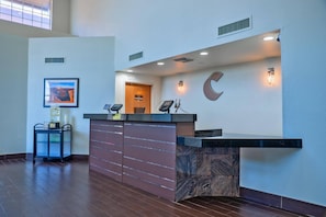A reception desk with a marble base, a framed picture on the wall, and a cart with items. - Comfort Inn & Suites Sierra Vista Near Ft Huachuca (Sierra Vista)