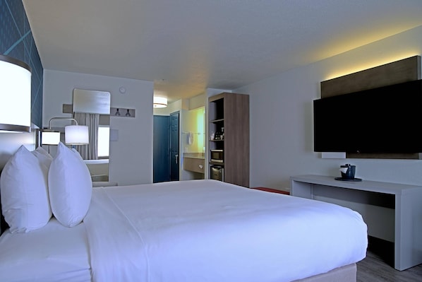 Una habitación de hotel con cama, televisión, escritorio y armario.