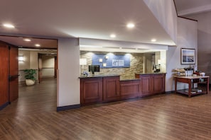 A reception area with a stone wall, wooden reception desk, and a framed picture on the wall. - Holiday Inn Express & Suites Carpinteria by IHG (Carpinteria)