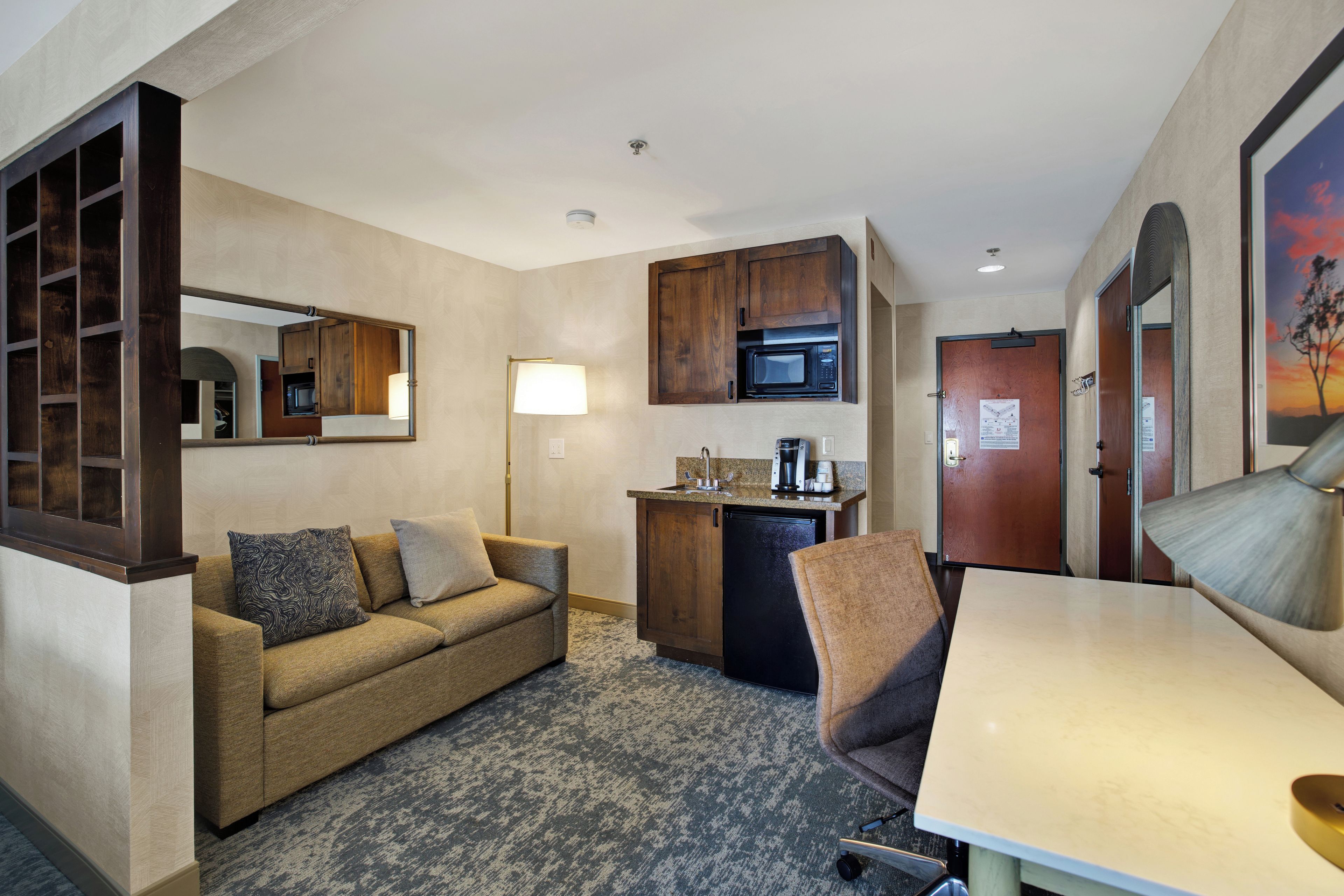 A compact living space with a kitchenette, a sofa, a dining table, and a mirror.