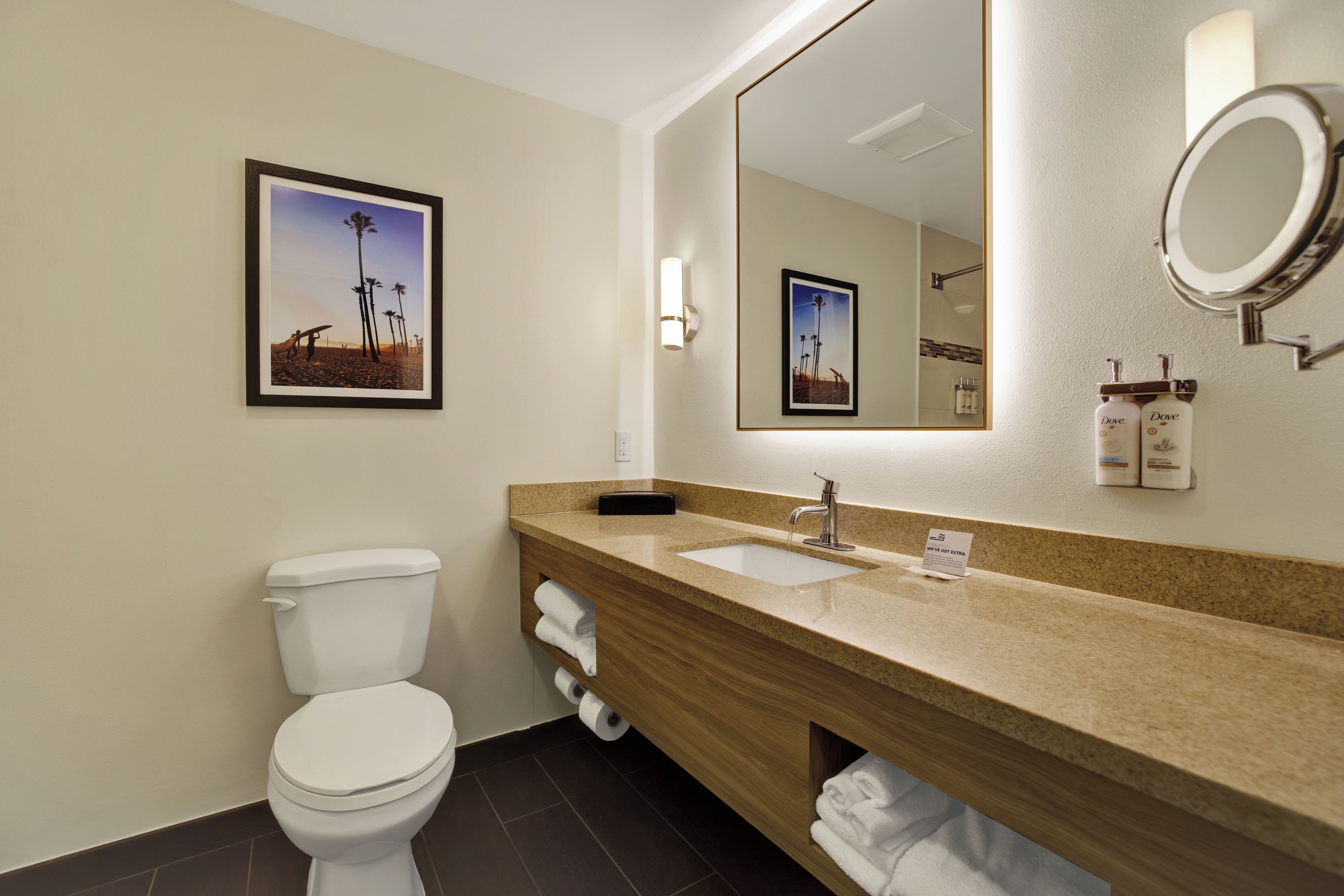 Un baño de hotel con inodoro, lavamanos y espejo.