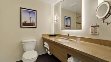 Une salle de bain d’hôtel équipée de toilettes, d’un lavabo et d’un miroir.